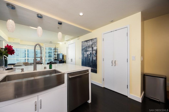 kitchen featuring dark wood-type flooring, sink, stainless steel dishwasher, decorative light fixtures, and white cabinetry