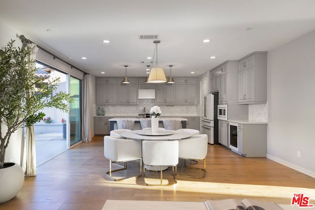 kitchen with decorative light fixtures, light wood-type flooring, gray cabinets, and high end white refrigerator