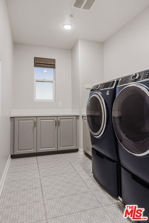 washroom featuring cabinets, light tile patterned floors, and washing machine and clothes dryer