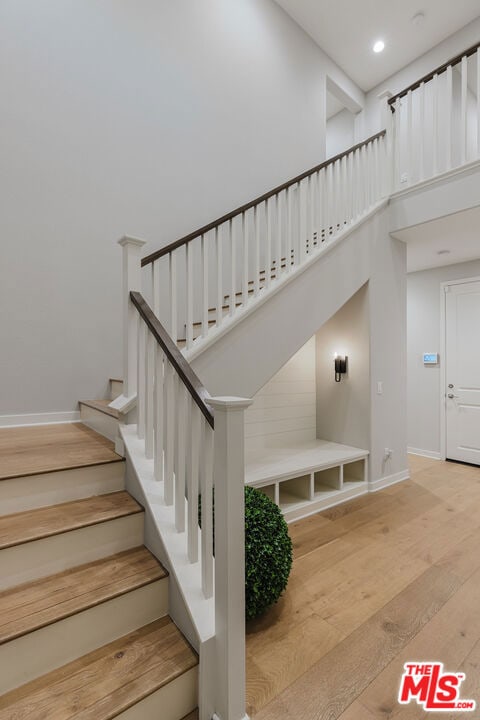 stairway featuring a towering ceiling and hardwood / wood-style flooring