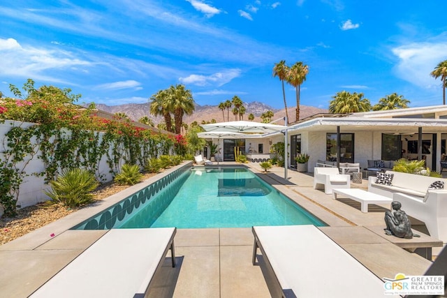 view of swimming pool featuring an outdoor living space, ceiling fan, a mountain view, and a patio