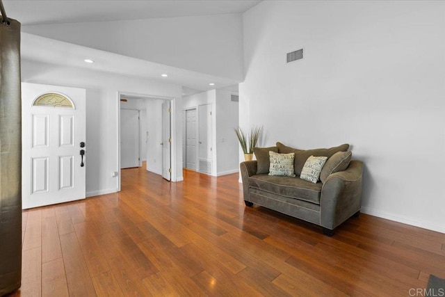 living area with hardwood / wood-style floors and high vaulted ceiling