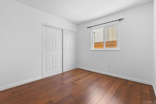 unfurnished bedroom with dark hardwood / wood-style floors and a closet