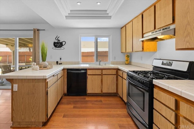 kitchen featuring stainless steel gas range oven, sink, light hardwood / wood-style flooring, black dishwasher, and kitchen peninsula