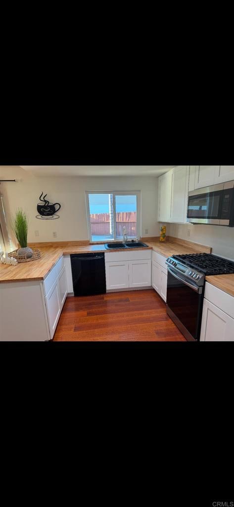 kitchen with white cabinets, appliances with stainless steel finishes, and wooden counters