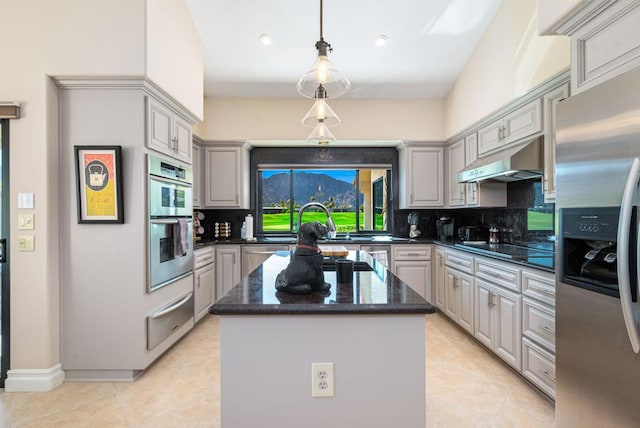 kitchen with appliances with stainless steel finishes, a kitchen island, tasteful backsplash, light tile patterned floors, and gray cabinetry