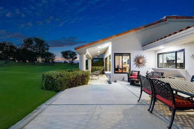 patio terrace at dusk featuring a yard