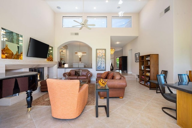 living room featuring ceiling fan, a high ceiling, and light tile patterned floors