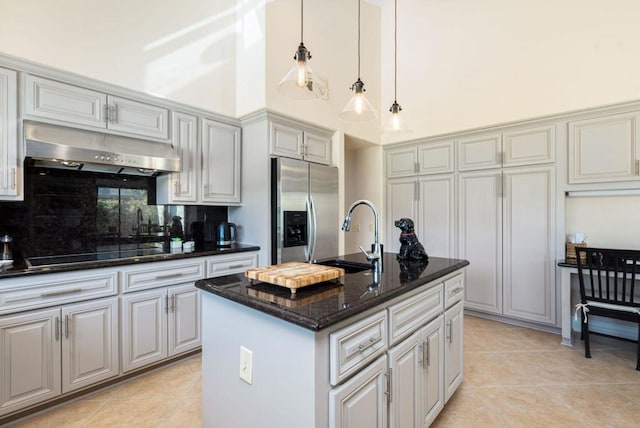 kitchen featuring stainless steel refrigerator with ice dispenser, sink, tasteful backsplash, an island with sink, and black electric cooktop