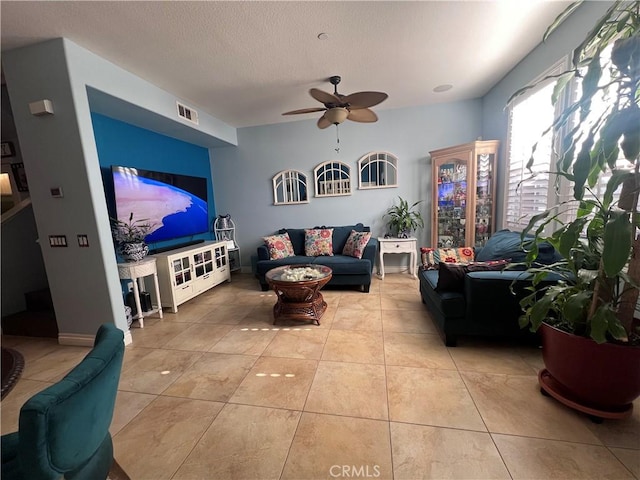 living room with a textured ceiling, ceiling fan, and light tile patterned flooring