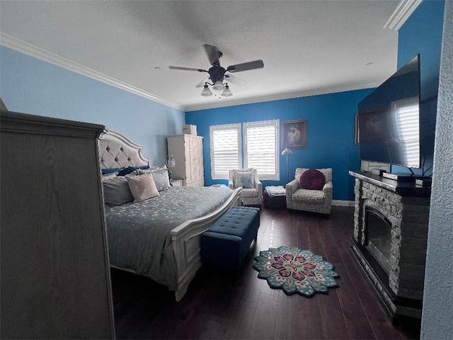 bedroom with a stone fireplace, ceiling fan, dark hardwood / wood-style floors, and ornamental molding