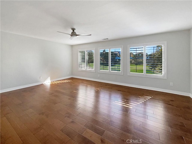 spare room with dark hardwood / wood-style floors, a wealth of natural light, and ceiling fan