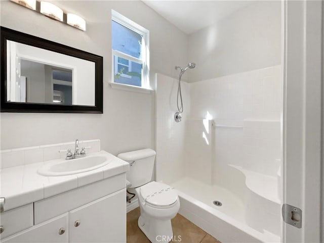 bathroom featuring tile patterned flooring, a shower, vanity, and toilet