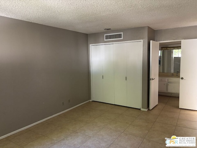 unfurnished bedroom featuring light tile patterned floors, a textured ceiling, and a closet