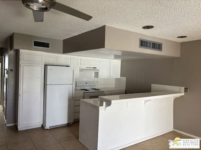 kitchen featuring tile countertops, kitchen peninsula, white cabinets, and white appliances