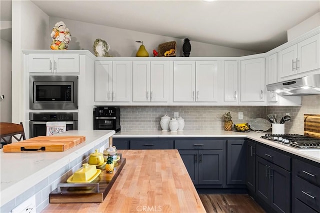 kitchen featuring tasteful backsplash, white cabinets, vaulted ceiling, and stainless steel appliances