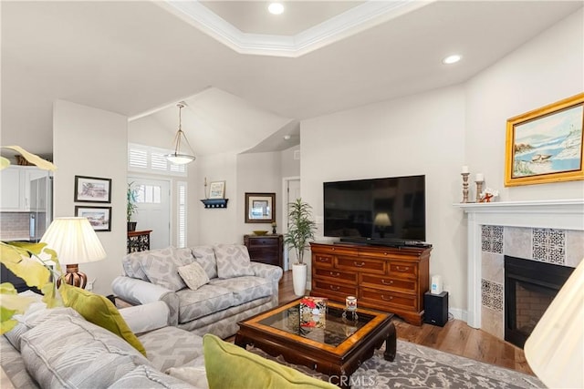 living room featuring crown molding, light hardwood / wood-style floors, and a tiled fireplace