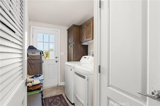 clothes washing area with cabinets, washer and dryer, and tile patterned floors