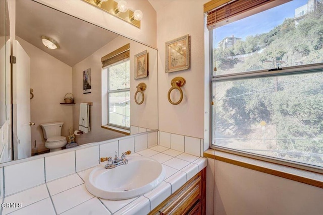 bathroom with vanity, toilet, and vaulted ceiling