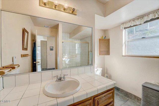 bathroom featuring tile patterned flooring, vanity, and a shower with shower door