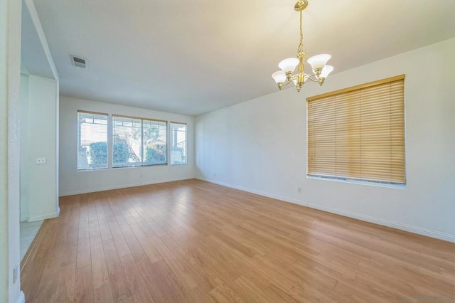 unfurnished room with light hardwood / wood-style flooring and a notable chandelier