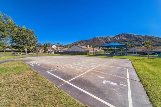 view of community featuring a lawn, a mountain view, a playground, and basketball court