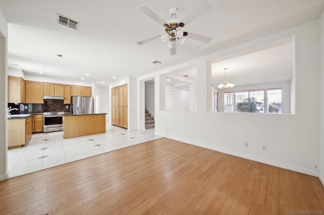 kitchen with backsplash, ceiling fan with notable chandelier, sink, light hardwood / wood-style floors, and stainless steel appliances