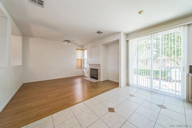 unfurnished living room with a tile fireplace, ceiling fan, and light hardwood / wood-style flooring