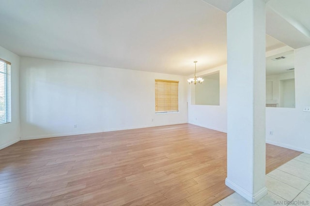 unfurnished room featuring a chandelier and light wood-type flooring