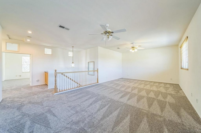 carpeted empty room with ceiling fan and plenty of natural light