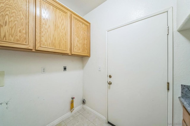 laundry area with electric dryer hookup, light tile patterned flooring, and cabinets