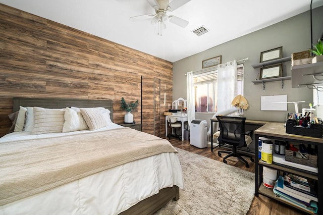 bedroom featuring ceiling fan, wood walls, and dark hardwood / wood-style flooring