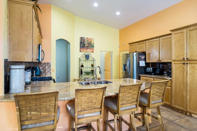 kitchen with sink, light stone counters, kitchen peninsula, a breakfast bar, and appliances with stainless steel finishes