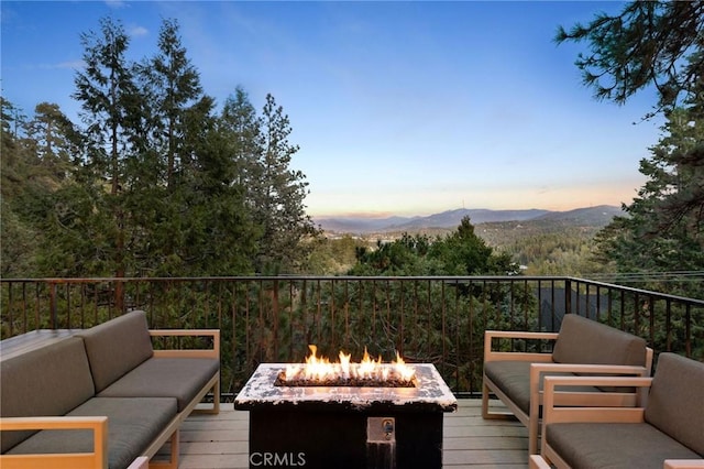 deck at dusk featuring a mountain view and an outdoor living space with a fire pit