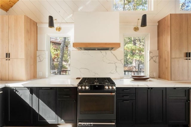 kitchen with backsplash, light stone counters, stainless steel gas stove, and custom exhaust hood