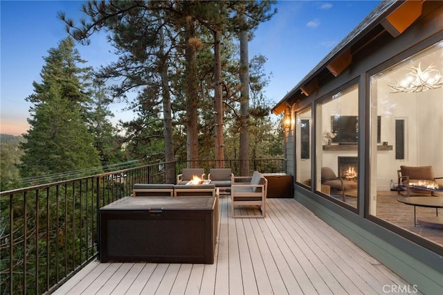 deck at dusk with an outdoor living space with a fire pit