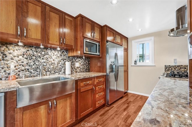 kitchen featuring stainless steel appliances, light stone counters, and light hardwood / wood-style floors