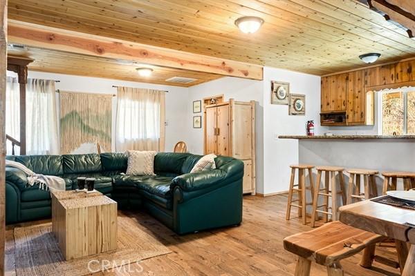 living room featuring beamed ceiling, hardwood / wood-style flooring, and wood ceiling