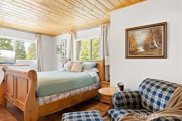 bedroom featuring multiple windows, hardwood / wood-style floors, and wooden ceiling