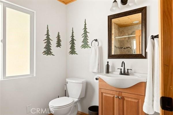 bathroom with tiled shower, vanity, and toilet