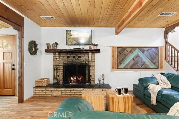 living room with hardwood / wood-style flooring, wood ceiling, and a brick fireplace