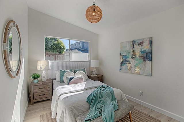 bedroom with vaulted ceiling and light wood-type flooring