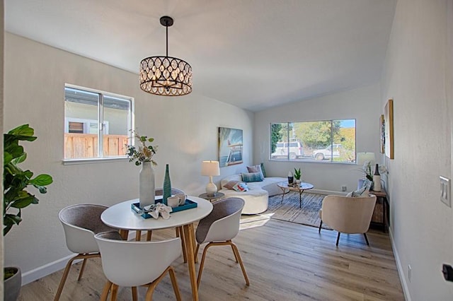 dining space with lofted ceiling, a chandelier, and light wood-type flooring