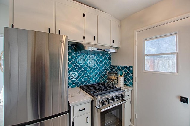 kitchen with tasteful backsplash, appliances with stainless steel finishes, white cabinets, and light stone counters