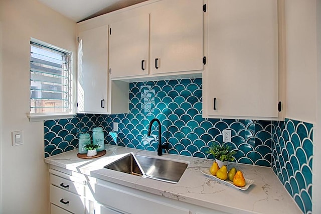 kitchen with tasteful backsplash, sink, and light stone countertops