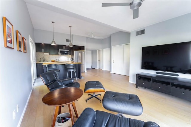 living room with light hardwood / wood-style flooring, ceiling fan, and sink