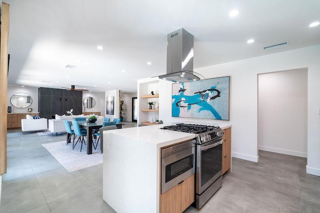 kitchen featuring island exhaust hood, ceiling fan, a center island, and stainless steel range with gas stovetop