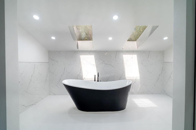 bathroom with a washtub and tile walls