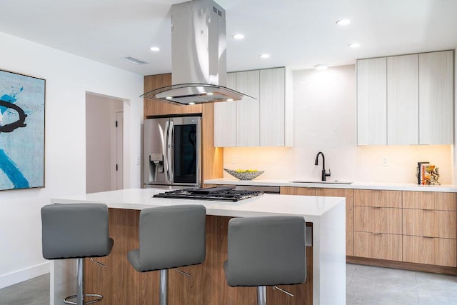 kitchen with a kitchen bar, stainless steel appliances, island range hood, sink, and a center island