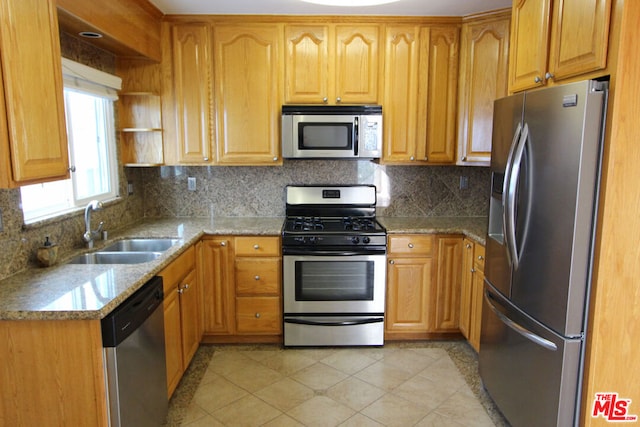 kitchen featuring light stone countertops, appliances with stainless steel finishes, decorative backsplash, and sink